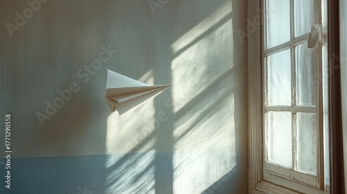 Paper airplane soaring on a sunlit wall near a vintage window, symbolizing dreams and freedom