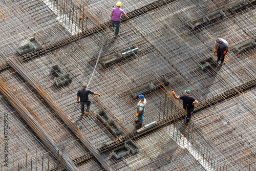 A construction crew is laying a metal mesh for pouring concrete to create a monolithic overlap between the floors of a high-rise building