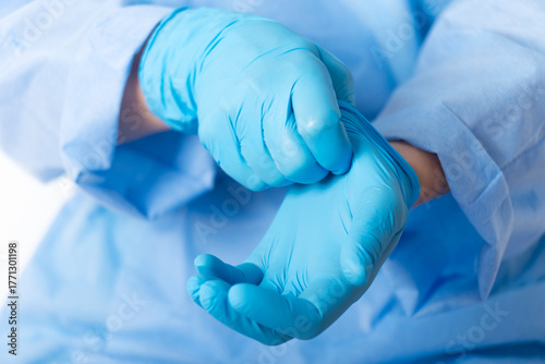 Healthcare professional putting on blue medical gloves on white background with copy space