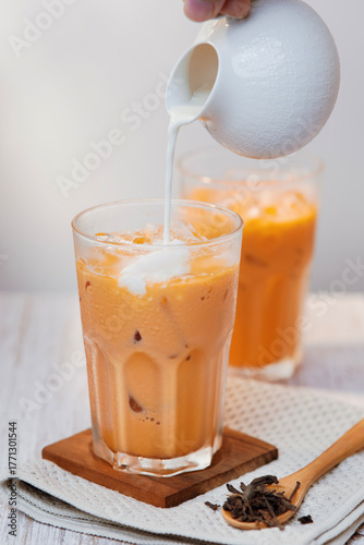 Thai tea with milk in a glass jar placed on a wooden table