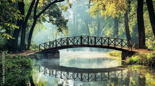Picturesque wooden bridge arches gracefully over a tranquil misty river reflecting lush forest