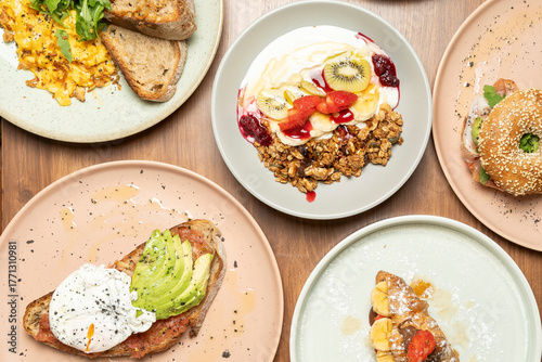 Various plates of delicious healthy breakfast and brunch food on a wooden table