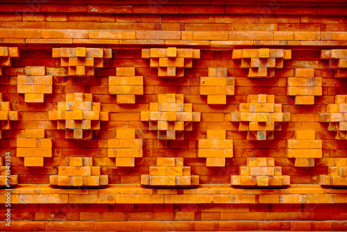Close-up of a traditional Balinese brick wall with intricate geometric patterns, showcasing weathered texture and warm earthy tones