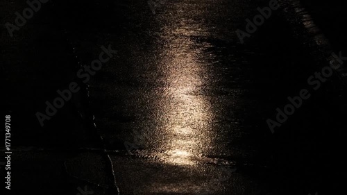 Rain fall on city street asphalt at night. Close up, telephoto footage, top down, real time, no people