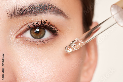 Young beautiful woman applying face serum with pipette. Cosmetic procedures for facial skin care