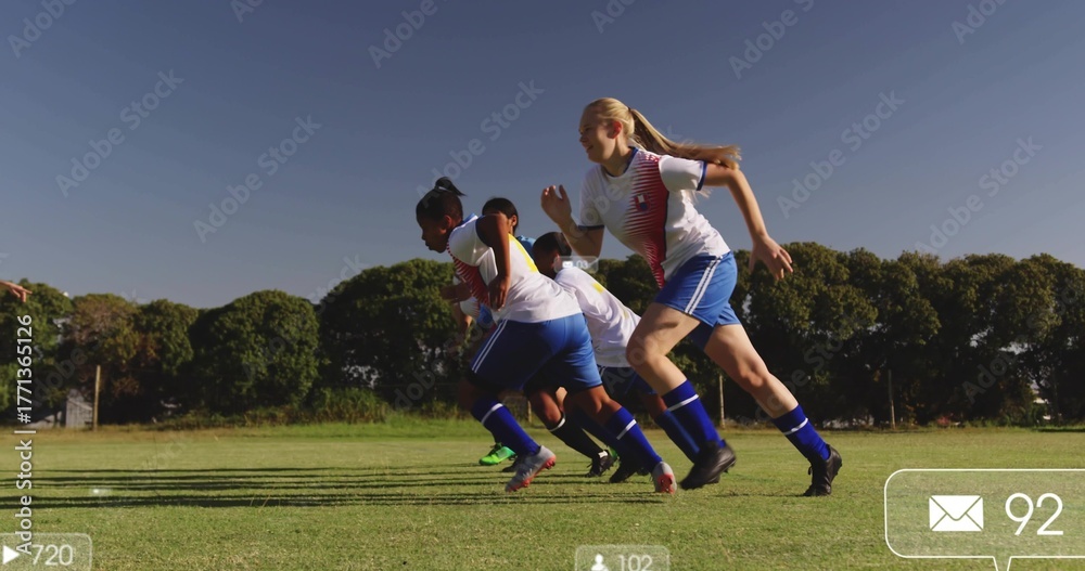 Obraz premium Sprinting five female soccer teammates on grassy soccer field, wearing soccer uniforms and cleats