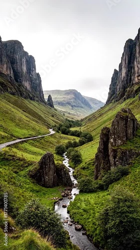 A winding road through a valley, flanked by towering cliffs and a flowing river