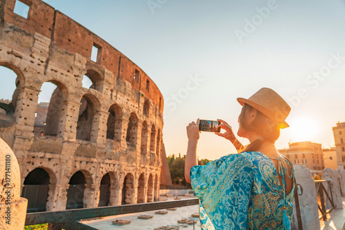 08 08 2025 Rome, Italy - Female tourist taking picture of Colosseum at dusk
