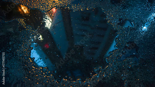 View of city buildings reflected on the surface of water on the street.