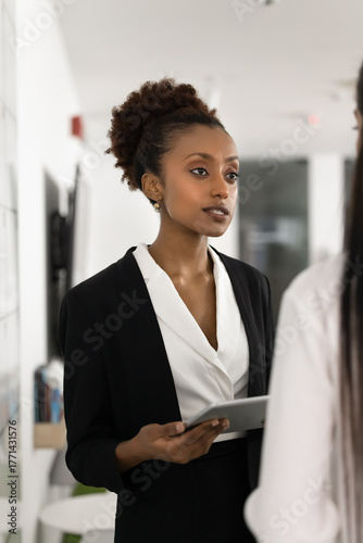 Confident female business professional standing at workplace talking to client