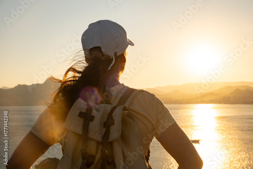 Woman enjoys golden sunset view from a coastal cliff 