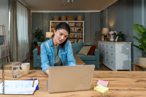 Carta da parati Freelance businesswoman in home office reviewing charts and dictating a voice no