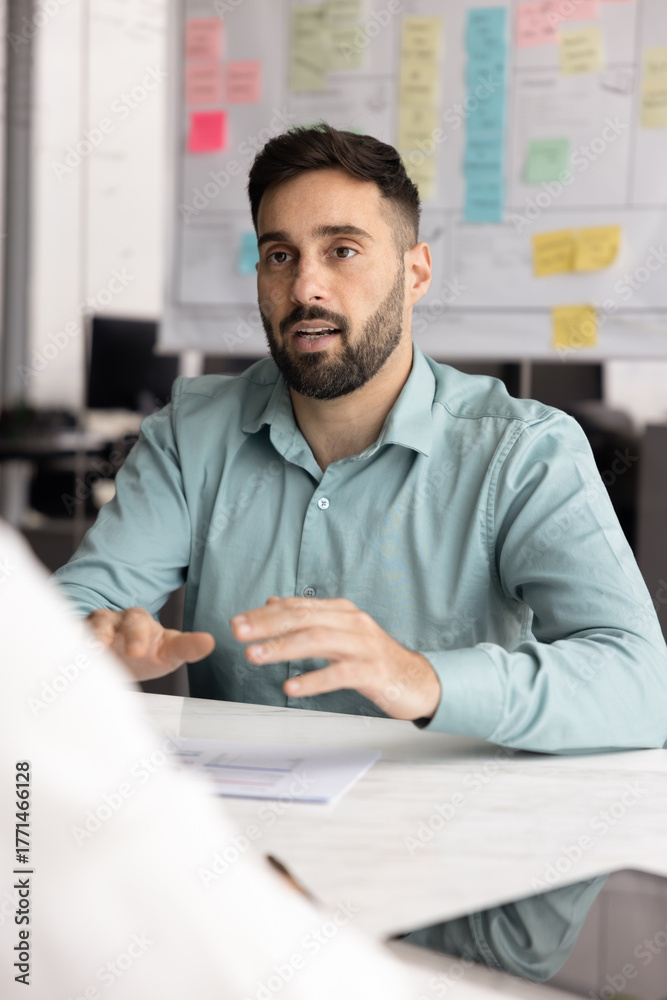 Naklejka premium Portrait focused young male business professional speak sitting at desk