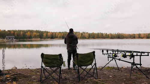 Fisherman casting rod on calm autumn lake, outdoor recreation and fishing sport scene with professional gear and forest reflections, peaceful nature and lifestyle activity concept
