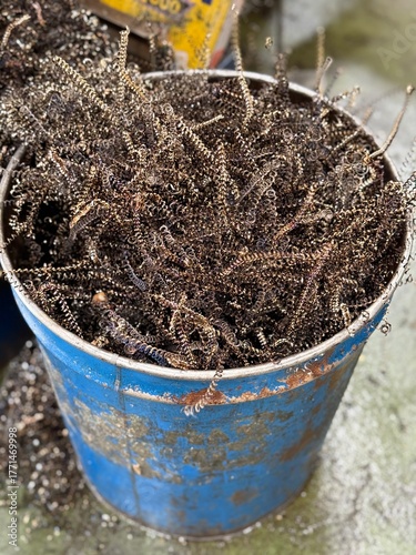 Blue metal bin containing scrap metal from turning workpieces