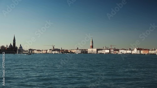 Various ships and boats sail in azure Venetian lagoon against city landmarks time-lapse. Busy water transport traffic in sea harbor on St Mark Campanile backdrop. Marine scene