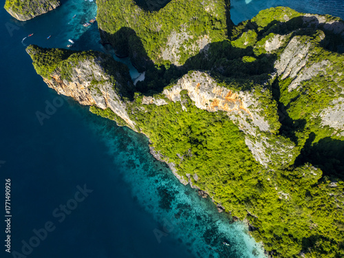 Aerial view of vibrant green foliage contrasts with the rugged cliffs and turquoise waters of Phi Phi Islands, Krabi, Thailand.