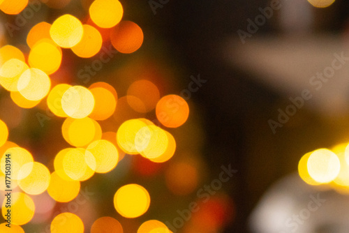 Defocused golden yellow lights creating bokeh effect on dark background. Abstract Christmas festive mood decoration. Happy New Year celebration.