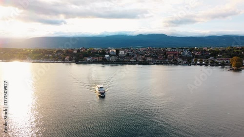 Wallpaper Mural Aerial view of a passenger boat sailing on Lake Geneva towards the cityscape of Nyon, framed by mountains under a cloudy sky, Nyon, Vaud, Switzerland. Torontodigital.ca