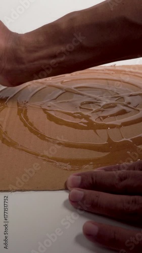 Close up of hands applying rat glue to cardboard, ready for pest control and rodent trapping.