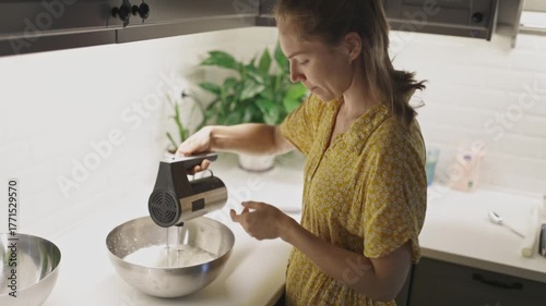 Woman using electric mixer for baking in modern kitchen