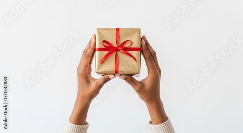 Woman holding a golden gift box with red ribbon on white background. Holiday present for birthday, Christmas, or anniversary.