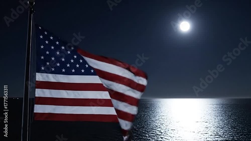 American flag waves proudly under a bright full moon over calm ocean waters at night