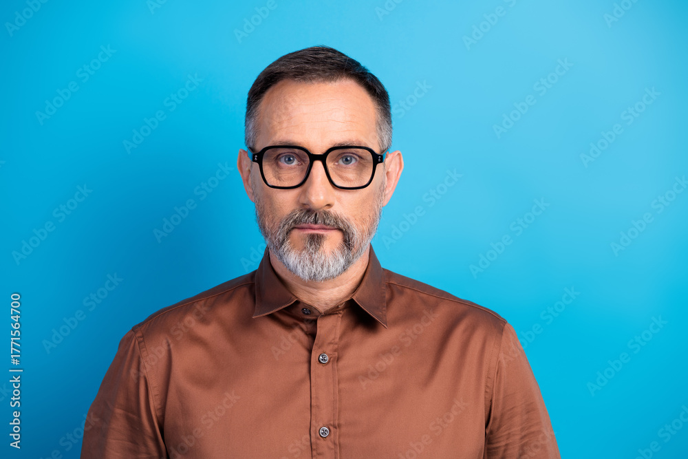Fototapeta premium Confident mature business professional wearing brown shirt and glasses against blue background for corporate headshot and office lifestyle