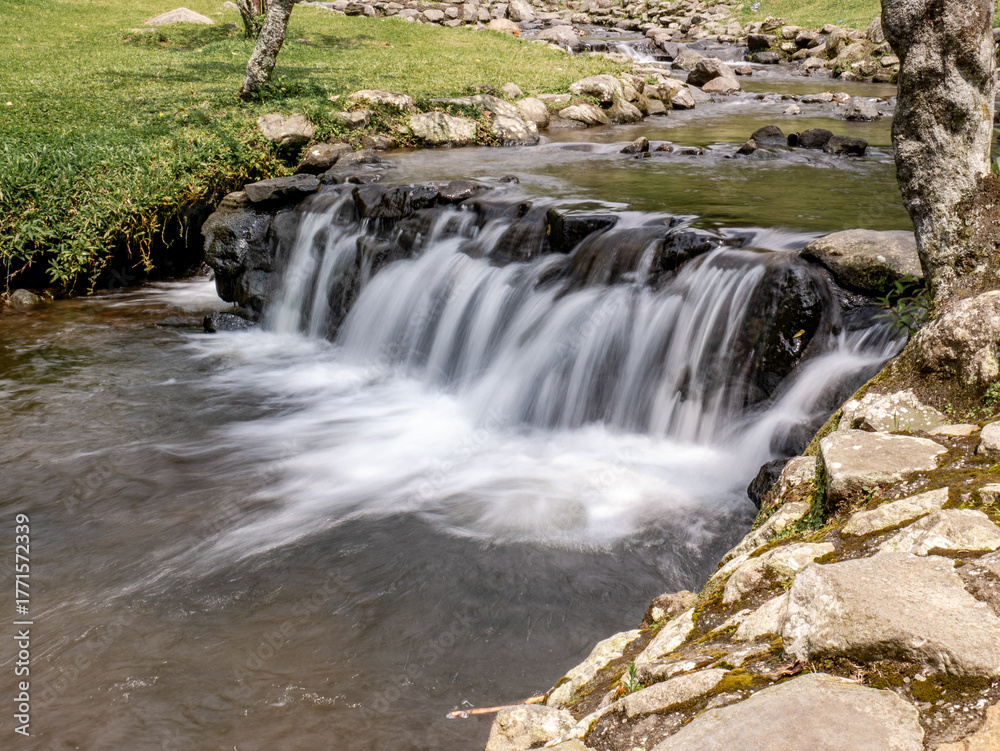 Fototapeta premium Soft waterfall in mountain botanical park with natural tones and calm atmosphere, great for travel visuals and eco lifestyle content