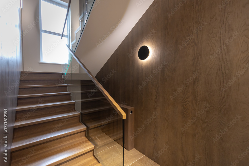 Fototapeta premium Wooden staircase with glass railings and wooden handrail.
