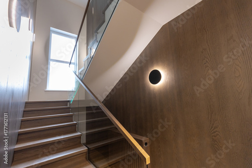 Wooden staircase with glass railings and wooden handrail.