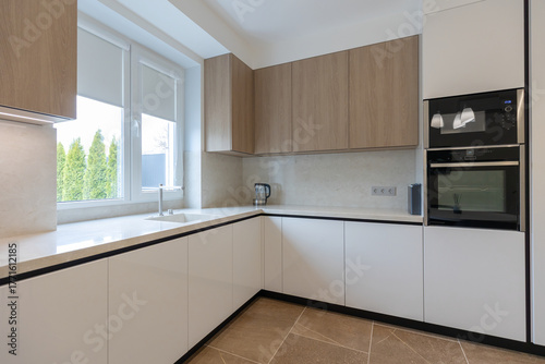 Modern and minimalist kitchen with white furniture, wooden elements.
