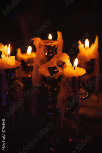 Burning candles in metal candlestick with melted wax