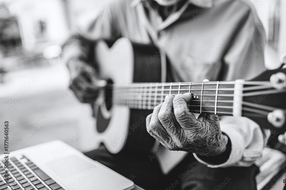 Fototapeta premium Macro of grandfather’s hands pressing guitar strings, laptop blurred in background, soft sunlight on wood guitar, muted beige and teal tones, focus on tactile learning.