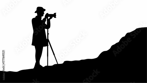 Silhouette photographer capturing scenic views with professional camera on tripod atop hill