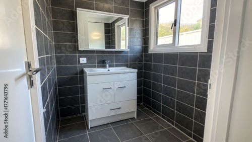 Modern bathroom with black tiles and a white vanity.