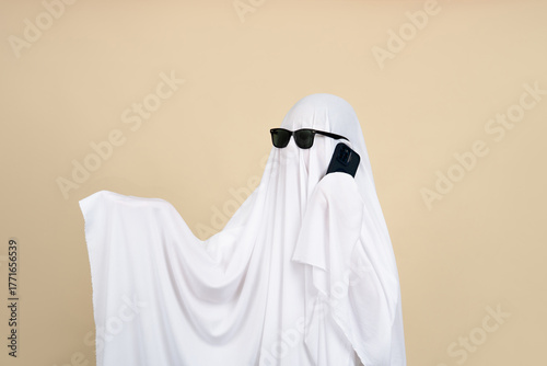 Creepy ghost. Person covered with white sheet on beige background