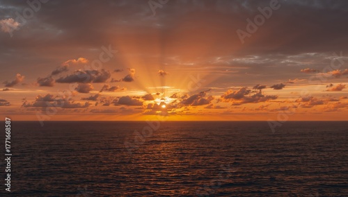 An Orange Haze, Soft Clouds, and Sun Rays Over the Ocean Horizon, Calm Waters.