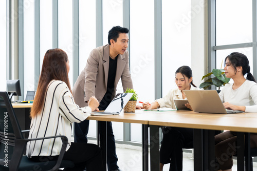 A group of professionals engage in a collaborative meeting in a modern office. The scene highlights teamwork, leadership, dynamic communication in a productive corporate environment.