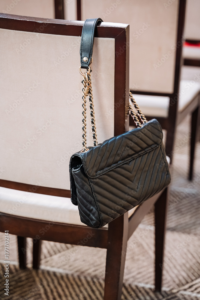 Naklejka premium elegant purse on cozy chair, luxury designer handbag beside plush carpet in sophisticated room