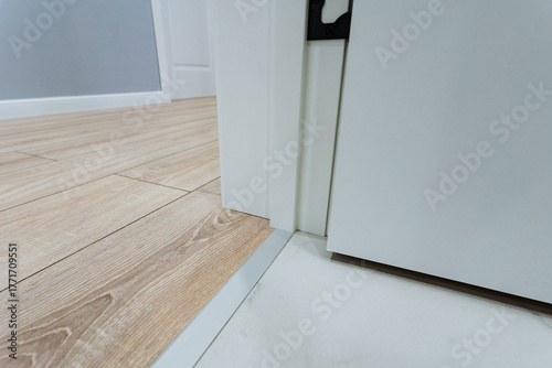 Tableau sur toile floor transition detail, closeup of door threshold connecting tile and wooden fl