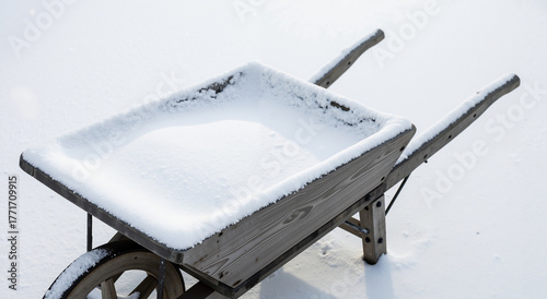 Wooden wheelbarrow filled with snow on a white background  