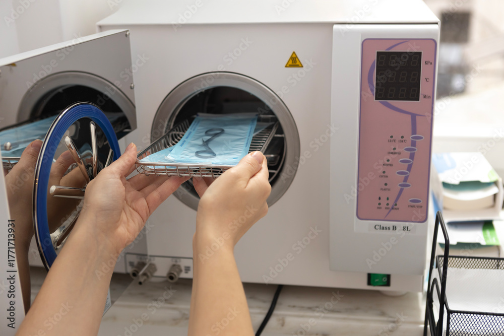 Ταπετσαρία Hands handling sterilization tray in a dental clinic's autoclave machine during