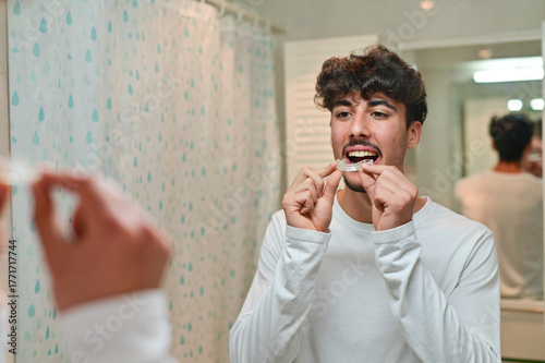 A man looking at the mirror with dental aligner retainer, dental clinic for beautiful teeth, treatment course.