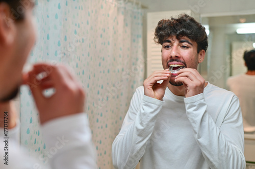 A man looking at the mirror with dental aligner retainer, dental clinic for beautiful teeth, treatment course.