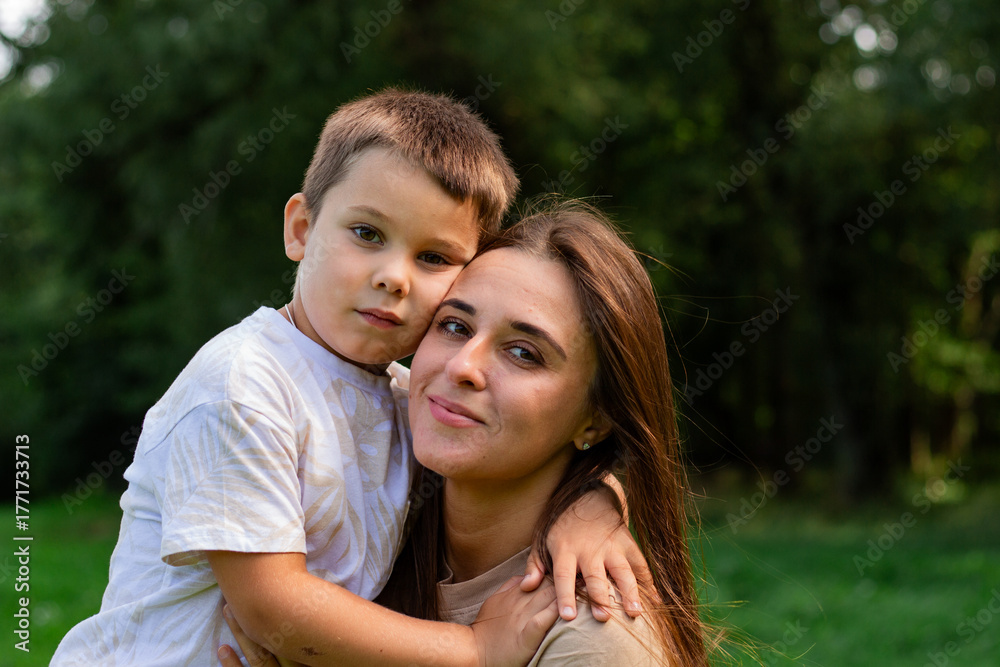 Obraz premium Mother kissing her cute preschool son on cheek. Candid portrait of parent and child. Mother's Day Concept