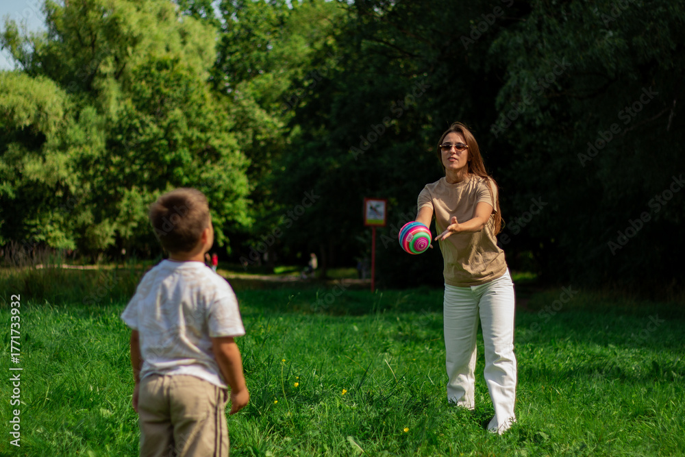Fototapeta premium Active lifestyle of mom and son. Energetic scene of mother and boy running and kicking ball on sunny day. Ideal for themes of health, fitness, sports, and active living for all ages.