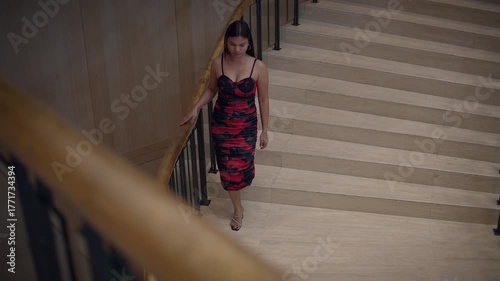 elegant woman descends stairs, elegant asian woman in red attire descends marble staircase