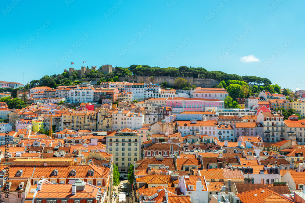 Obraz premium Panoramic view of Lisbon city with red rooftops and Sao Jorge Castle on the hill, Lisboa, Portugal. Old town skyline of Portuguese architecture in Alfama district. Travel and tourism in Europe