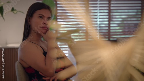 woman in lobby, reflective woman seated in modern reception area surrounded by greenery and cozy
